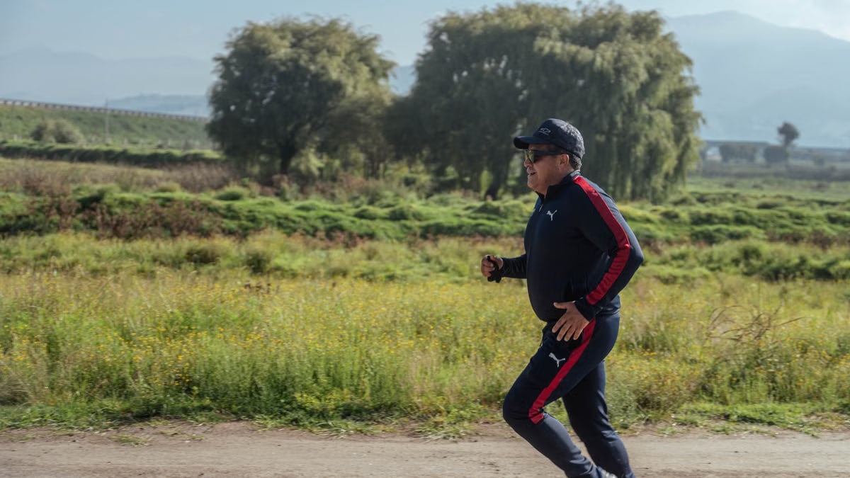 A man in sportswear jogging on a scenic rural path during the day.